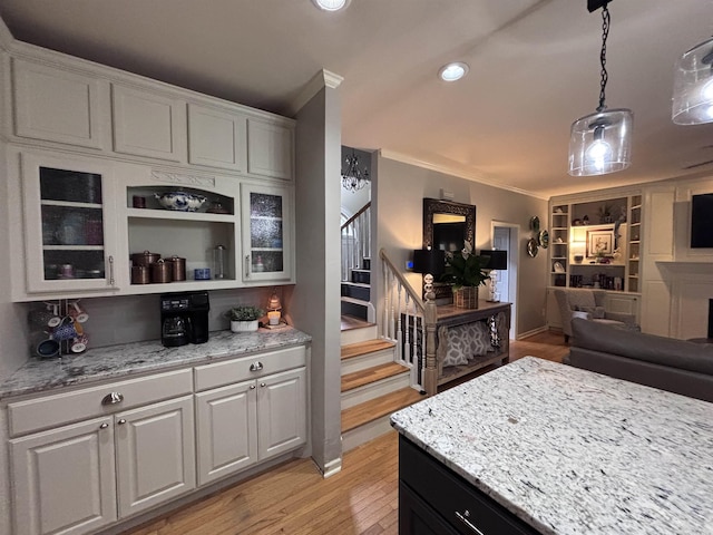 615 Miller Cv, Benton, AR 72019 - kitchen featuring glass insert cabinets, ornamental molding, open floor plan, light stone countertops, and light wood finished floors