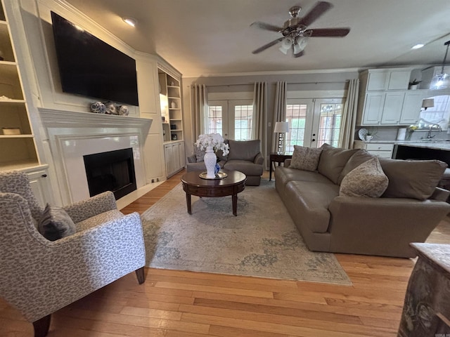 615 Miller Cv, Benton, AR 72019 - living room with a ceiling fan, light wood finished floors, a fireplace, built in shelves, and french doors