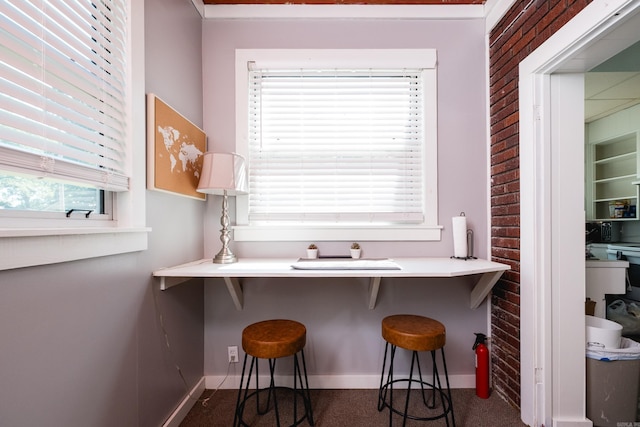 1224 S Fillmore St, Little Rock, AR 72204 - kitchen with carpet floors, baseboards, a breakfast bar area, and brick wall