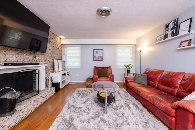 1224 S Fillmore St, Little Rock, AR 72204 - living room with wood finished floors, a textured ceiling, a brick fireplace, and baseboards