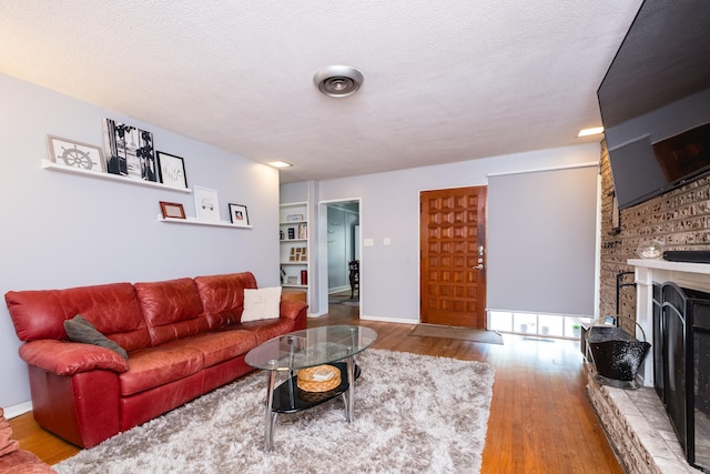 1224 S Fillmore St, Little Rock, AR 72204 - living room featuring a fireplace with raised hearth, wood finished floors, baseboards, and a textured ceiling