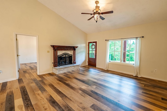 unfurnished living room featuring a ceiling fan, wood finished floors, a stone fireplace, baseboards, and high vaulted ceiling