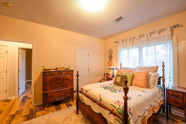 bedroom with wood finished floors and a textured ceiling