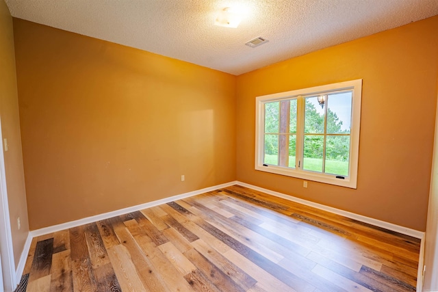 empty room featuring wood finished floors, baseboards, and a textured ceiling