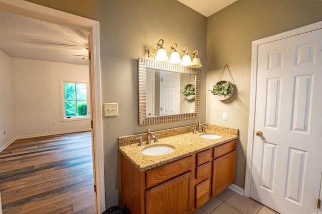 bathroom with double vanity, baseboards, and wood finished floors
