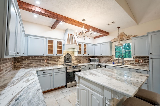 kitchen featuring stainless steel appliances, a sink, custom range hood, tasteful backsplash, and a chandelier