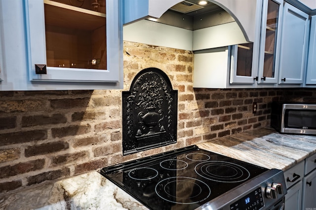 kitchen featuring electric range, glass insert cabinets, custom range hood, and stainless steel microwave