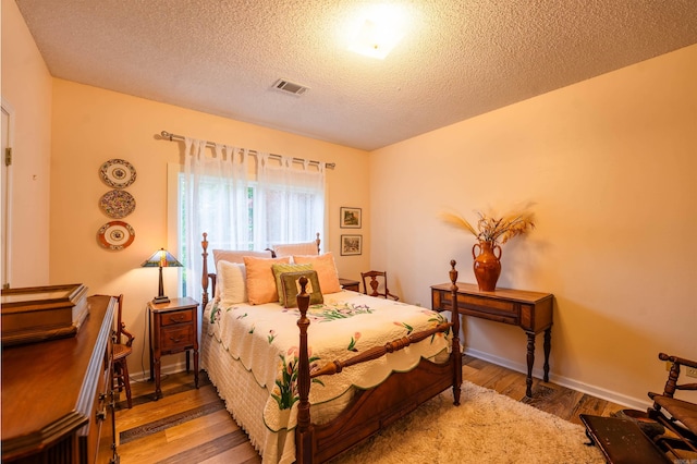 bedroom featuring wood finished floors, a textured ceiling, and baseboards