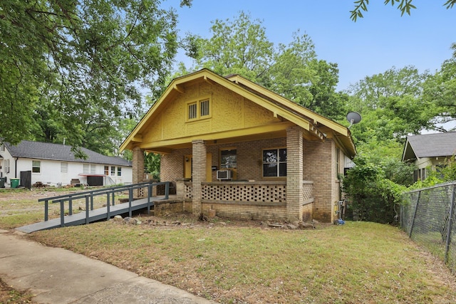 view of front of home with brick siding, a porch, and cooling unit