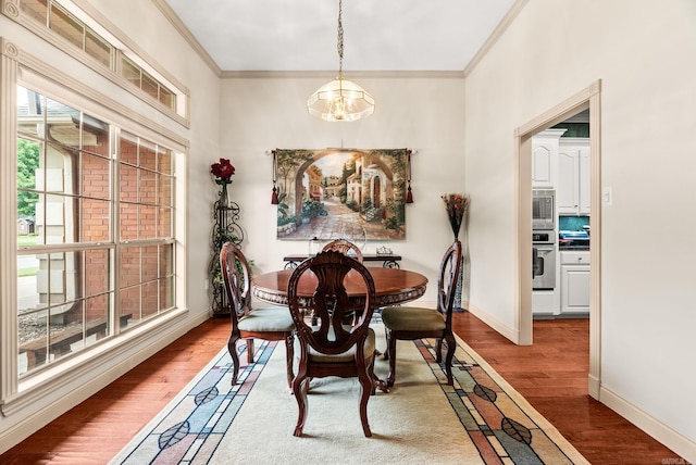 dining room featuring wood finished floors, crown molding, a chandelier, and baseboards