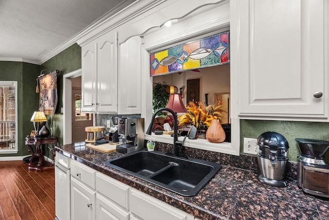 kitchen featuring a sink, dark countertops, dark wood finished floors, white cabinetry, and ornamental molding