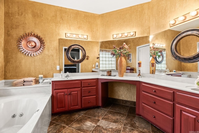 bathroom featuring a tub with jets, vanity, and a textured wall