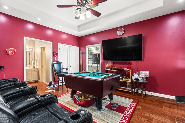 recreation room featuring billiards, a raised ceiling, wood finished floors, a ceiling fan, and baseboards