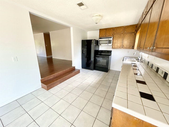 806 Autumnwood Rd, Ash Flat, AR 72513 - kitchen featuring tile counters, black appliances, a sink, brown cabinetry, and light tile patterned floors