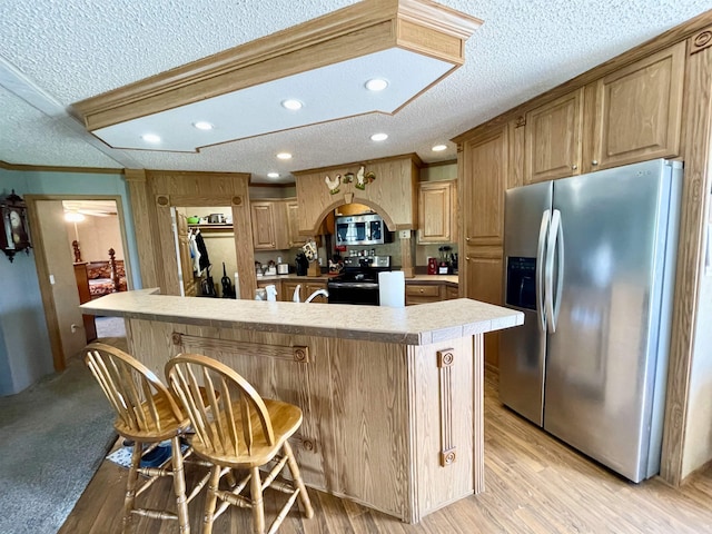 806 Autumnwood Rd, Ash Flat, AR 72513 - kitchen with appliances with stainless steel finishes, a textured ceiling, light countertops, a center island with sink, and a breakfast bar