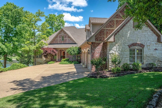 26 Pillar Ln, Hot Springs Village, AR 71909 - tudor home with stone siding, driveway, a front lawn, an attached garage, and a shingled roof