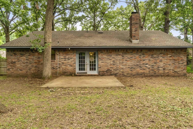 back of house featuring a chimney, a shingled roof, a patio area, french doors, and brick siding