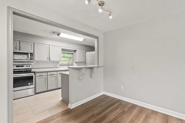 1118 Garland, North Little Rock, AR 72216 - kitchen featuring appliances with stainless steel finishes, gray cabinetry, baseboards, a peninsula, and light wood finished floors
