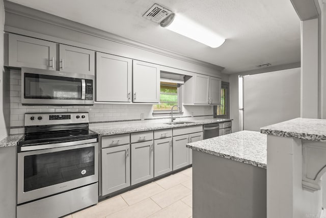 1118 Garland, North Little Rock, AR 72216 - kitchen featuring appliances with stainless steel finishes, decorative backsplash, a sink, gray cabinets, and light stone countertops