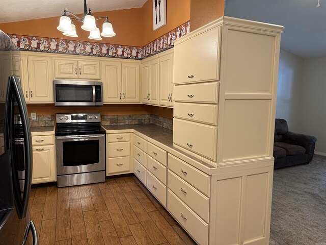 122 Meadow Cliff Cir, Fairfield Bay, AR 72088 - kitchen featuring stainless steel appliances, a chandelier, dark countertops, pendant lighting, and dark wood-style floors