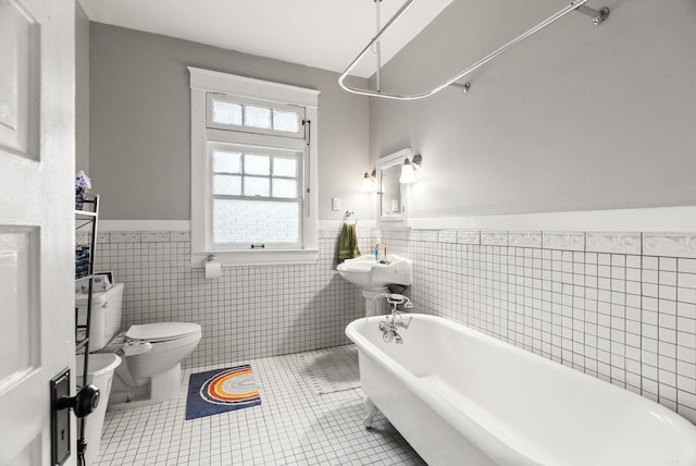 1905 S Battery St, Little Rock, AR 72202 - bathroom with toilet, a wainscoted wall, a soaking tub, tile walls, and tile patterned floors