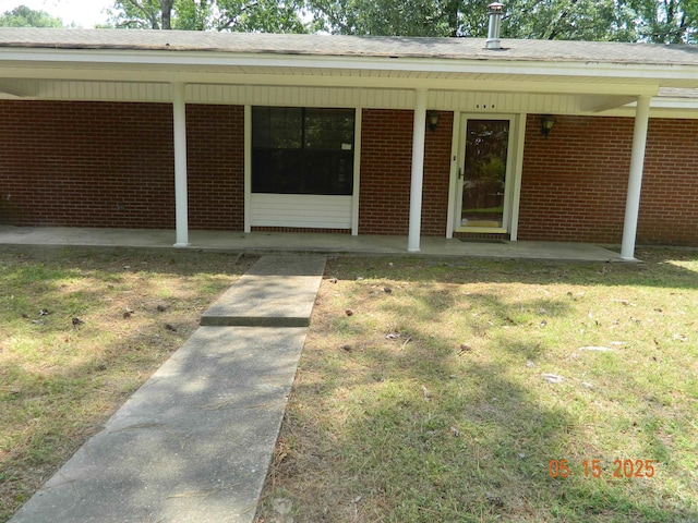 102 Turtle Creek Dr, Gurdon, AR 71743 - view of exterior entry with brick siding, a yard, and a patio area