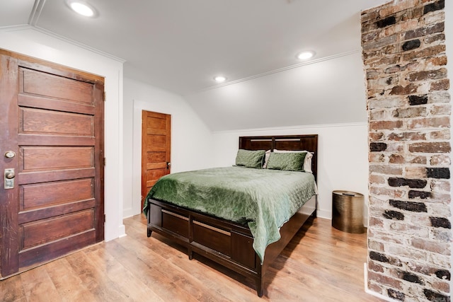 bedroom with vaulted ceiling, wood finished floors, recessed lighting, and crown molding
