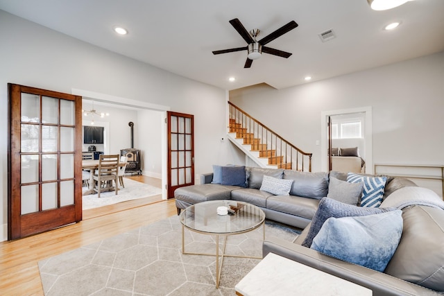 living room featuring a chandelier, light wood-type flooring, recessed lighting, stairs, and a ceiling fan