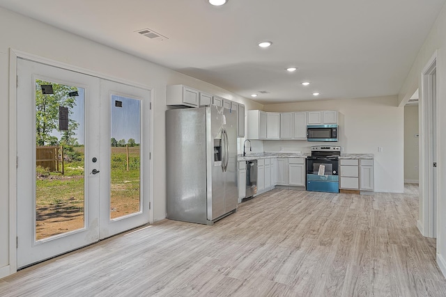 kitchen featuring appliances with stainless steel finishes, light countertops, light wood-style flooring, a sink, and recessed lighting