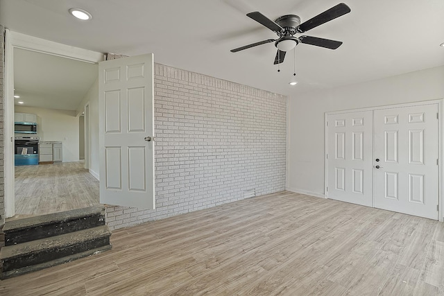 unfurnished bedroom with wood finished floors, brick wall, recessed lighting, ceiling fan, and a closet