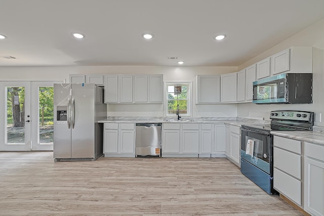kitchen with appliances with stainless steel finishes, a sink, light wood-type flooring, recessed lighting, and french doors