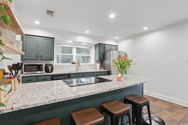 4911 B St, Little Rock, AR 72205 - kitchen with stainless steel appliances, a kitchen bar, decorative backsplash, dark wood-style floors, and crown molding