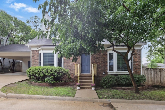 4911 B St, Little Rock, AR 72205 - view of property hidden behind natural elements featuring fence, concrete driveway, an attached carport, and brick siding