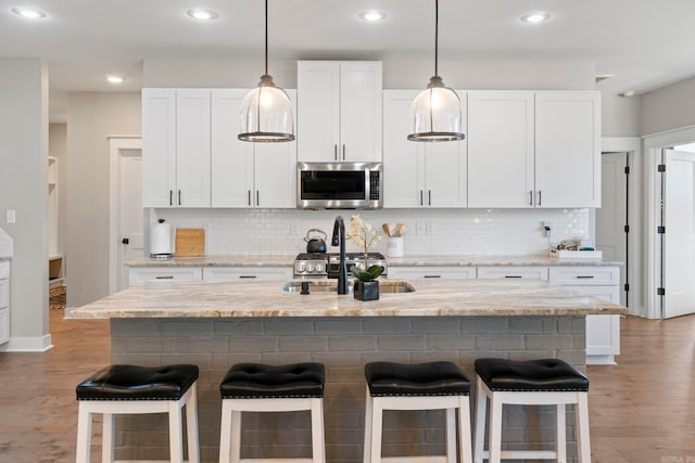 5101 Peace Ln, Alexander, AR 72002 - kitchen with stainless steel microwave, a sink, backsplash, a kitchen breakfast bar, and recessed lighting