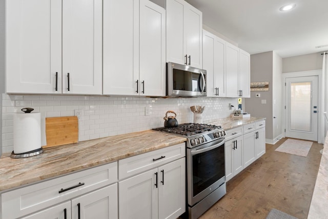 5101 Peace Ln, Alexander, AR 72002 - kitchen with stainless steel appliances, white cabinets, decorative backsplash, light wood-style floors, and light stone counters