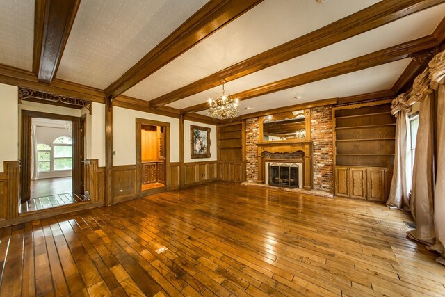 5401 N Hills Blvd, North Little Rock, AR 72116 - unfurnished living room featuring a chandelier, hardwood / wood-style floors, beam ceiling, wainscoting, and built in features