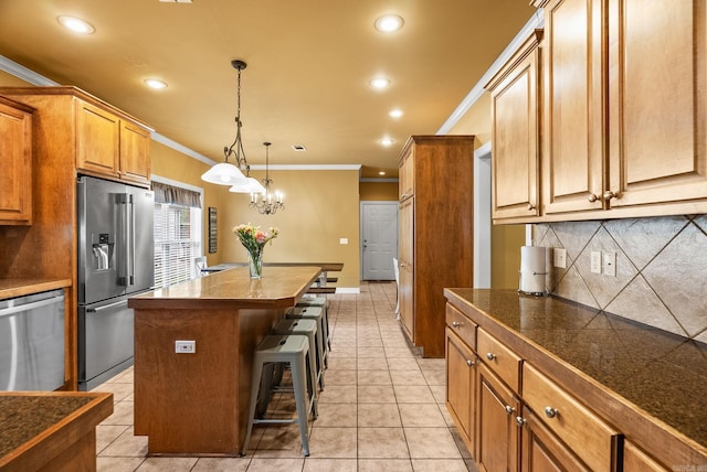 121 Lily Dr, Maumelle, AR 72113 - kitchen with appliances with stainless steel finishes, crown molding, a kitchen island, decorative backsplash, and tile counters