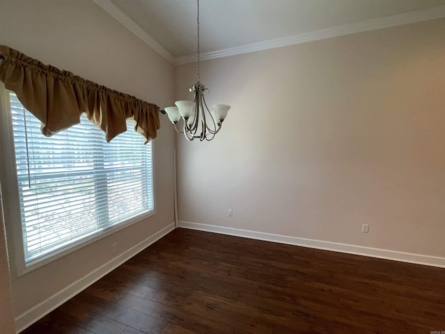 empty room featuring a chandelier, dark wood finished floors, ornamental molding, and baseboards