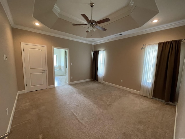empty room featuring a tray ceiling, healthy amount of natural light, ceiling fan, light colored carpet, and crown molding