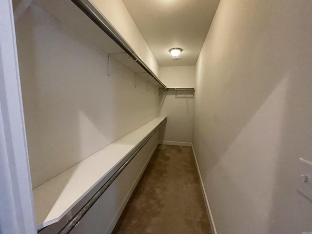 walk in closet featuring dark colored carpet