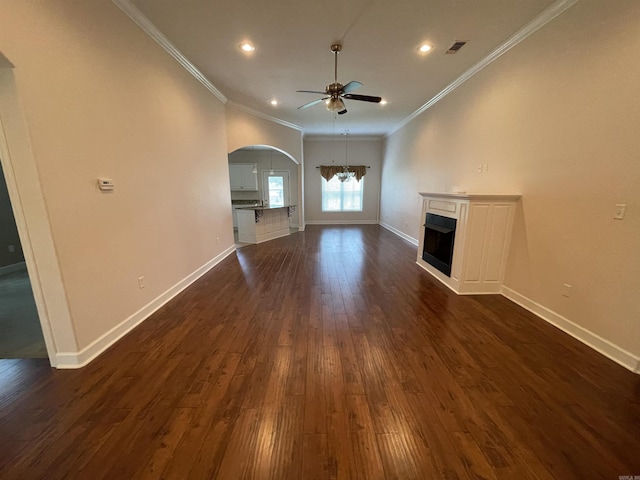 unfurnished living room featuring a ceiling fan, ornamental molding, a fireplace, arched walkways, and dark wood-style floors