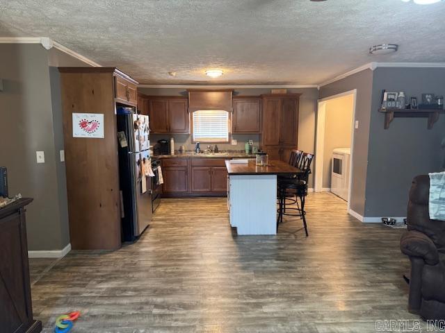 21 Emma Dr, Pocahontas, AR 72455 - kitchen with freestanding refrigerator, a kitchen bar, a textured ceiling, wood finished floors, and crown molding
