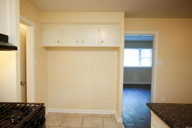 6914 Juniper Rd, Little Rock, AR 72209 - kitchen with white cabinetry, baseboards, dark stone countertops, and under cabinet range hood