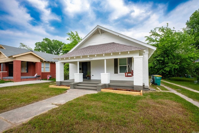 1407 Hanger St, Little Rock, AR 72202 - view of front of property featuring a porch, brick siding, roof with shingles, and a front yard