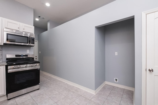 1407 Hanger St, Little Rock, AR 72202 - kitchen with appliances with stainless steel finishes, white cabinets, light tile patterned floors, light stone counters, and baseboards