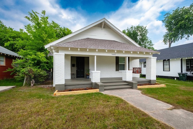 1407 Hanger St, Little Rock, AR 72202 - view of front of house featuring covered porch, brick siding, a shingled roof, and a front lawn