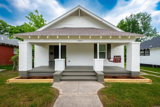 1407 Hanger St, Little Rock, AR 72202 - view of front facade featuring a porch, brick siding, roof with shingles, and a front yard