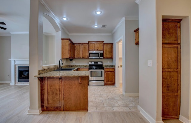 106 Venezia Ln, Maumelle, AR 72113 - kitchen with appliances with stainless steel finishes, a peninsula, brown cabinets, a sink, and light stone countertops
