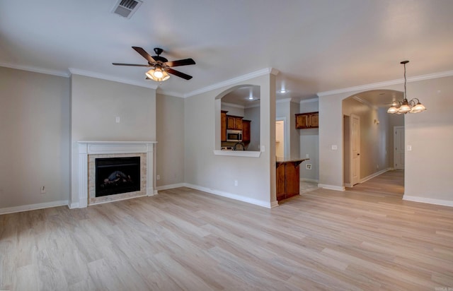 106 Venezia Ln, Maumelle, AR 72113 - unfurnished living room with light wood finished floors, a ceiling fan, a tile fireplace, arched walkways, and ornamental molding