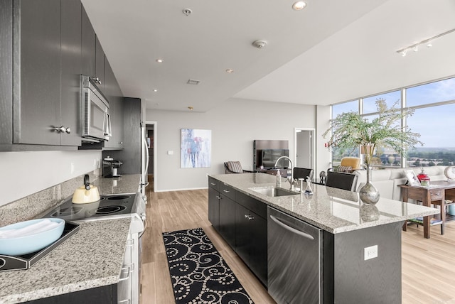 300 E Third # 1302, Little Rock, AR 72201 - kitchen with stainless steel appliances, a sink, a kitchen island with sink, dark cabinets, and light wood-style floors
